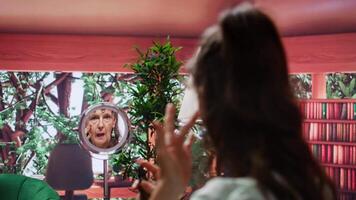 Senior woman looking in the mirror and applying anti aging cream on her face, using rejuvenating products to preserve her skin. Pensioner doing pampering routine with serum and lotion. Camera B. video