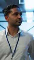 Vertical Admin walking amidst server rows, looking to ensure optimal performance and reliability by implement and managing gear. IT staff member in data center overseeing high tech facility, camera A video