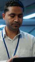 Vertical Engineer walking in data center, monitoring security threats, implementing cybersecurity measures. Indian man ensuring compliance with regulations to protect data center gear, camera A video