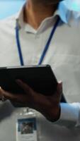 Vertical Software developer walking in data center, managing and maintaining databases, ensuring data integrity and security. Close up of man updating server room mainframe systems using tablet, camera A video