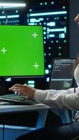 Vertical Technician doing checkup on green screen server hub PC to optimize it for data processing requirements of AI. Worker inspects data center used for machine learning using mockup computer, camera A video