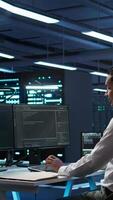 Vertical Data center agent providing logistics support to businesses and overseeing infrastructure. Server farm worker oversees hardware rackmounts and communicates with technicians, camera B video