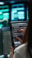Vertical Data center software developer responsible for installation of networking equipment solving tasks on device. Close up of woman doing maintenance on server room infrastructure using tablet, camera A video