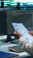 Vertical System administrator in data center maintaining accurate paperwork of hardware, generating reports. IT expert in high tech server farm doing workplace disaster recovery planning, camera A video