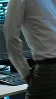 Vertical Engineer overseeing data center, making improvements and updates to ensure system can handle networking tasks, handheld camera shot. Indian man in server room tracking network traffic, camera A video