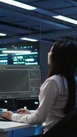 Vertical Engineer using augmented reality tech in data center, installing software, troubleshooting issues. IT expert in server hub looks at AR hologram, establishing performance benchmarks, camera B video