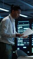 Vertical Admin in data center working with colleague to maintaining accurate documentation of equipment, generating reports. Server hub teamworking coworkers doing disaster recovery planning, camera A video
