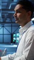 Vertical Engineer doing checkup on server hub to optimize it for data processing requirements of AI workloads. Hardworking employee inspects data center used for machine learning, camera B video