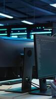 Vertical Multi monitor computer setup in data center used for monitoring security threats threatening rigs. Trucking right shot of PCs used by futuristic server hub admins ensuring compliance with regulations video