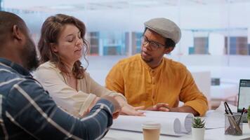 Professional clients and their real estate agent evaluating blueprints for the high class modern space, discussing leasing contract terms before signing. Startup business development. Camera B. video