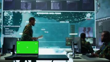 Military IT specialist in command center working on collecting field data, process real time surveillance footage and imagery for successful defense operation. Isolated mockup display on pc. Camera B. video