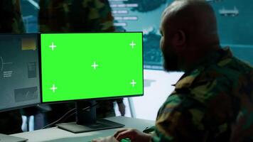 Military expert handles satellite cctv data next to mockup screen, working in a base of operations with high tech gear to support important defense missions. Coordinates strategic tactics. Camera A. video