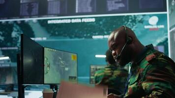 Military personnel operating in a secure office environment, processing critical information and data on big screen. Maintaining protocols essential for national defense and operations. Camera B. video