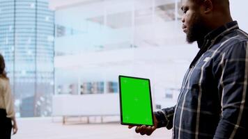 Real estate agents and client examine blueprints next to a green screen, working together on new modern office space development layout. Sharing workspace design vision. Camera A. video