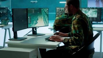 Military experts in mission control center use modern technology on computer and big screen, analyzing satellite footage. Specialist tracking potential threats for intelligence operations. Camera A. video