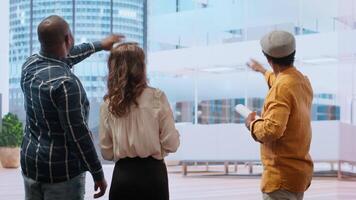 Corporate clients and a real estate agent negotiating a leasing contract, focusing on architectural blueprints, layout and investment potential of new office property. Hunting for deals. Camera A. video