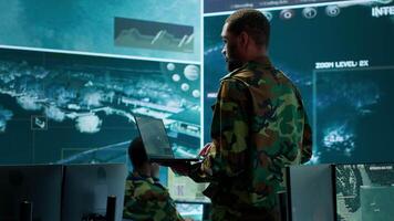 Team of military specialists operate in a secret service command post, managing surveillance systems and data protection to ensure the safety and security of classified information. Camera A. video