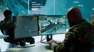 Military crew in a high tech operations command post managing information from radar cctv systems, real time data to support defense missions. Army protocols for national security. Camera A. video