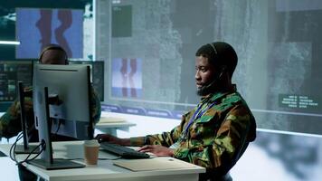 Team of military specialists in command post monitoring satellite data, integrates real time information from cctv footage. Decision making for strategic defense missions and security. Camera A. video