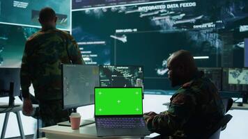 IT expert collecting real time information next to isolated chroma key screen, high tech gear in command post. Soldier processing intelligence for field operations and strategic missions. Camera B. video