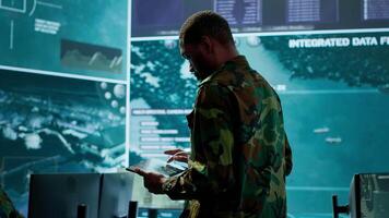 Cybersecurity specialist operates in a high tech military control center, monitoring surveillance footage and gathering intelligence for a new defense mission. Secret service activity. Camera A. video