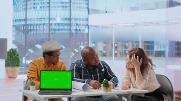 Diverse people meeting on an office tour next to laptop with green screen, realtors presenting the architectural blueprints to client. Businesswoman looking to invest in real estate. Camera B. video