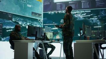 Team of military specialists operate in a secret service command post, managing surveillance systems and data protection to ensure the safety and security of classified information. Camera B. video