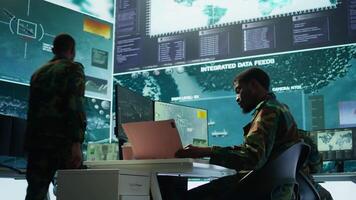 Military personnel in a control center working on data processing, integrating real time surveillance and security protocols essential for national defense and strategic operations. Camera B. video