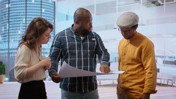 Real estate agent and clients discussing detailed blueprints for a new office property, evaluating architectural design and layout in modern high class building. Investment opportunity. Camera B. video