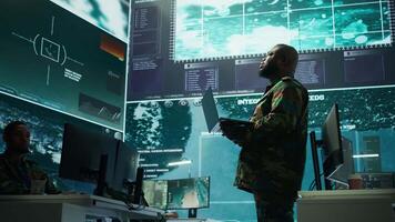 Military team manages cybersecurity operations in a high tech control center base of operations, managing data protection and surveillance systems, safeguarding national security. Camera B. video