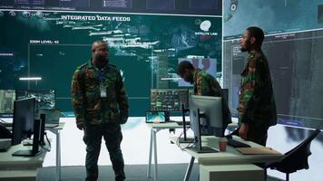Military personnel operate advanced systems in a command center, focusing on surveillance and data analysis to protect national security. Soldiers trained to manage information warfare. Camera B. video