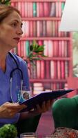 Vertical Nurse consulting a sick elderly man with oxygen tube and IV drip bag at home, paying a visit to offer assistance and support. Caregiver using an oximeter to examine health condition. Camera A. video