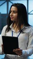 Vertical Admin in data center monitoring security threats with tablet, implementing cybersecurity measures. Specialist using device, ensuring compliance with regulations to protect data center gear, camera A video