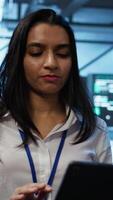 Vertical Engineer in high tech data center managing and maintaining databases, ensuring data integrity, security and availability. Indian woman updating server room supercomputers systems, camera B video