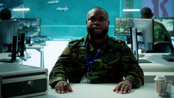 Reconnaissance expert engages in a online videocall in a high tech control room, coordinating intelligence and surveillance efforts with remote teams to enhance national defense program. Camera A. video