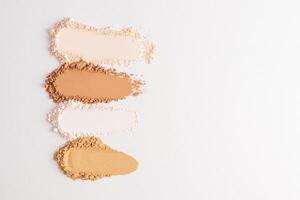 Several samples of loose powder in different tones on a white background with a copy space. . Layout, a sample for texture design and advertising. photo