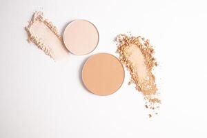 Two different samples of loose powder and two round blocks of compact powder in different tones on a white background. top view. Cosmetic texture photo
