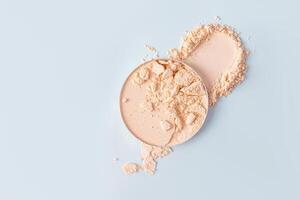 A chic example of the texture of a compact powder in a natural tone in a block and swatch on a blue background. top view. A copy space photo