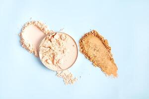 A chic example of the texture of a compact powder in a natural tone in a block and swatch on a blue background. top view. A copy space photo