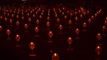 A large number of candles are lit at borobudur temple. The candles are arranged in a pattern, with some candles grouped together and others spaced apart. Scene is one of warmth and coziness photo