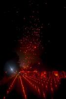 A large group of Buddhist people at Borobudur temple holding burning candles and lanterns. The scene is illuminated with warm, inviting light, creating a festive atmosphere photo