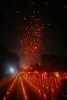 A large group of Buddhist people at Borobudur temple holding burning candles and lanterns. The scene is illuminated with warm, inviting light, creating a festive atmosphere photo