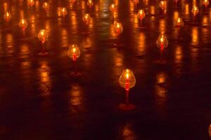 A large number of candles are lit at borobudur temple. The candles are arranged in a pattern, with some candles grouped together and others spaced apart. Scene is one of warmth and coziness photo