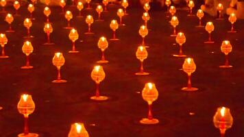 A large number of candles are lit at borobudur temple. The candles are arranged in a pattern, with some candles grouped together and others spaced apart. Scene is one of warmth and coziness photo