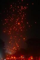 A large group of Buddhist people at Borobudur temple holding burning candles and lanterns. The scene is illuminated with warm, inviting light, creating a festive atmosphere photo