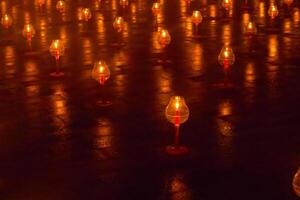 A large number of candles are lit at borobudur temple. The candles are arranged in a pattern, with some candles grouped together and others spaced apart. Scene is one of warmth and coziness photo