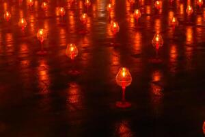 A large number of candles are lit at borobudur temple. The candles are arranged in a pattern, with some candles grouped together and others spaced apart. Scene is one of warmth and coziness photo