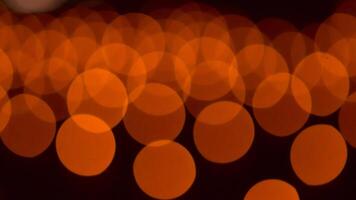 bokeh blurry, orange and black photo of a bunch of small circles. The circles are all different sizes and are scattered throughout the photo. Scene is somewhat chaotic and disorganized