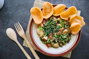 lotek is a traditional salad from Indonesia made from vegetable, chayote, kale, young jackfruit, tempeh, tofu, long beans, and bean sprouts with peanut sauce and cracker photo
