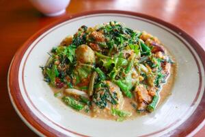 lotek is a traditional salad from Indonesia made from vegetable, chayote, kale, young jackfruit, tempeh, tofu, long beans, and bean sprouts with peanut sauce and cracker photo